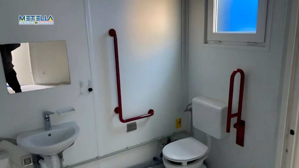 Interno di modulo bagno accessibile con wc e maniglioni di supporto