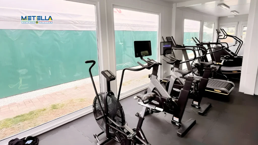 Interno di container palestra con macchinari cardio e spazio per allenamenti funzionali