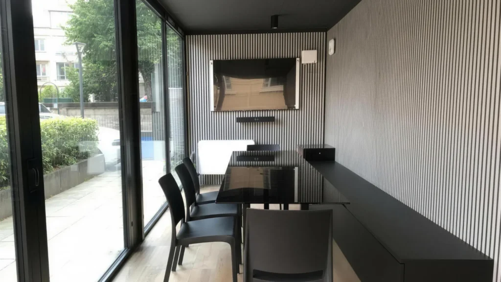 Interno sala riunioni con vetrata, ampio tavolo, sedie, panca, schermo led e rifiniture in legno